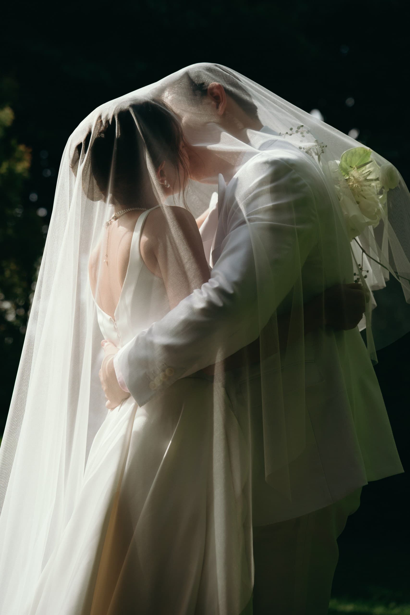 Cô dâu chú rể ôm nhau dưới voan cưới